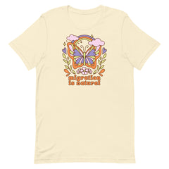 Retro style cream t-shirt with a vibrant butterfly and floral graphic centered around the message migration is natural in a 70s inspired aesthetic.