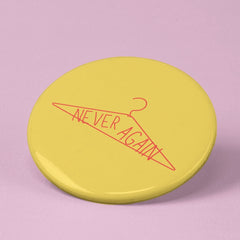 feminist pin that says never again inside a red coat hanger- shop feminist trash for pro choice pins and feminist tshirts