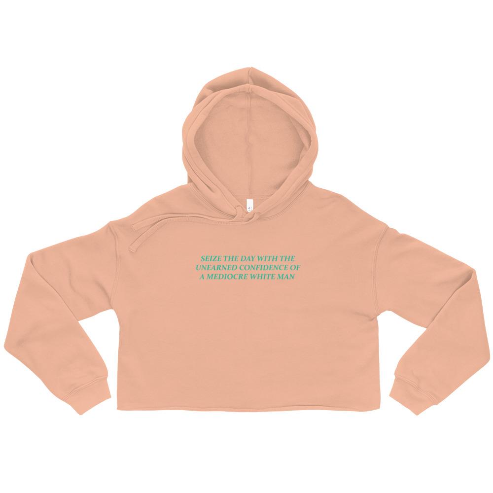 Peach feminist cropped hoodie featuring 'Seize the Day with the Unearned Confidence of a Mediocre White Man' text, empowering women to embrace their potential. Shop feminist apparel