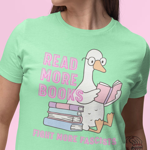 mint green antifa tshirt that says read more books fight more fascists in pink writing. Featuring a cute illustration of a goose reading. Shop feminist trash for political shirts 