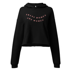 black hooded pride crop top that says trans women are women in orange wavy writing- shop feminist trash for pride merch and feminist tees