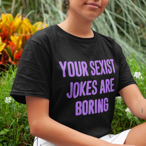 Black feminist shirt that says Your Sexist Jokes Are Boring in bold purple writing. Define feminism with our feminist apparel, political clothing, pride clothing, and dump him shirts