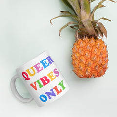 11 oz Pride mug that says Queer Vibes in rainbow retro writing- shop feminist trash for pride clothing, political t shirts, feminist apparel and dump him shirts