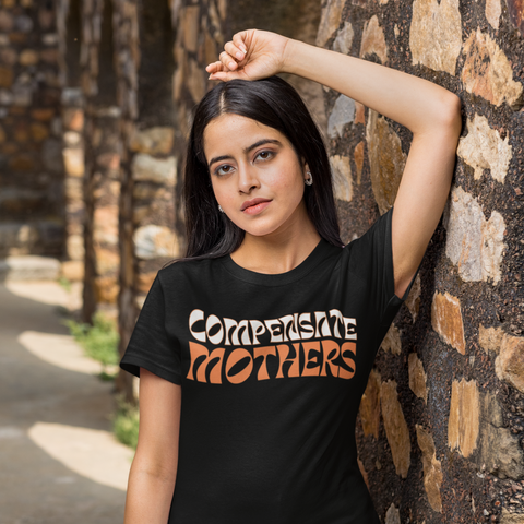 Black feminist tee that says Compensate Mothers in orange and white retro writing- Shop Women’s Rights T-shirts and women’s march merchandise 