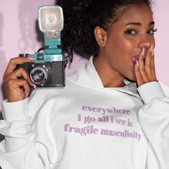 White feminist hoodie that says Everywhere I Go All I See Is Fragile Masculinity in purple lowercase font Shop Feminist apparel and dump him shirts