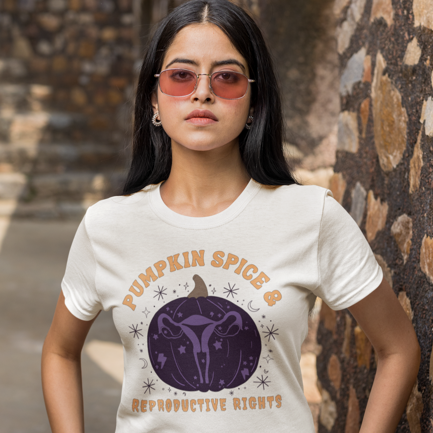 white feminist shirt that says pumpkin spice and reproductive rights in orange writing- featuring a purple pumpkin illustration with a uterus inside- shop feminist trash for halloween feminist tshirts and outfits for fall