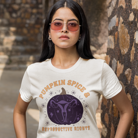 white feminist shirt that says pumpkin spice and reproductive rights in orange writing- featuring a purple pumpkin illustration with a uterus inside- shop feminist trash for halloween feminist tshirts and outfits for fall