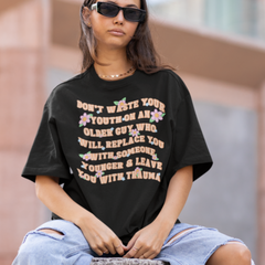 Black feminist tee that says Don’t Waste Your Youth On An Older Guy Who Will Replace You With Someone Younger And Leave You With Trauma in orange writing- Shop Women’s Rights T-shirts and Feminist Clothing